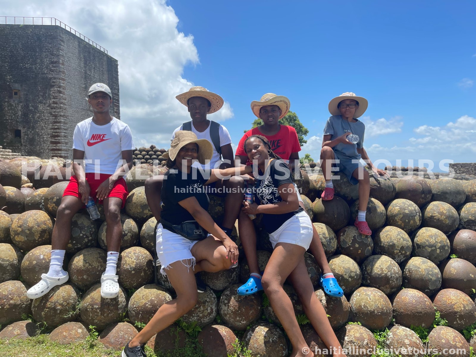 Guests seated on the cannonball pyramid at the Citadelle Laferrière above Milot