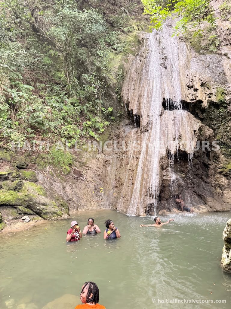 Guests swimming in the natural pool beneath a waterfall in Northern Haiti