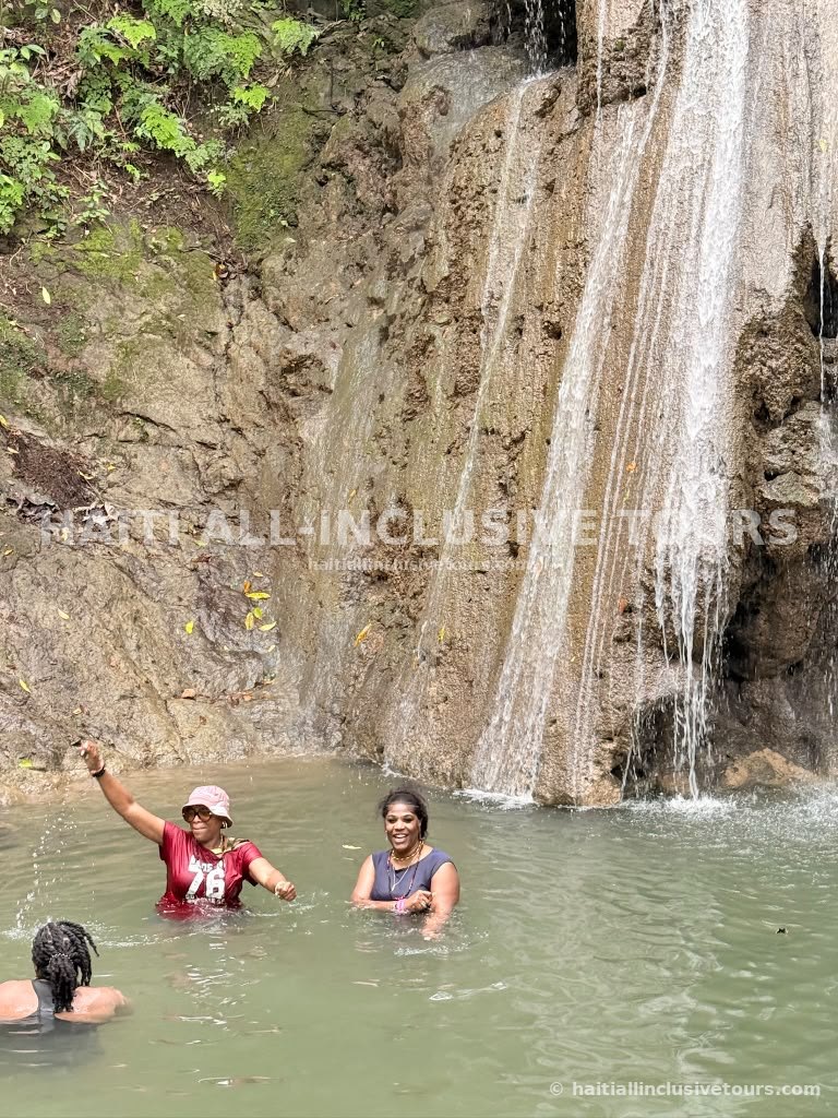 Guests laughing in the cool water at the base of a Haitian waterfall