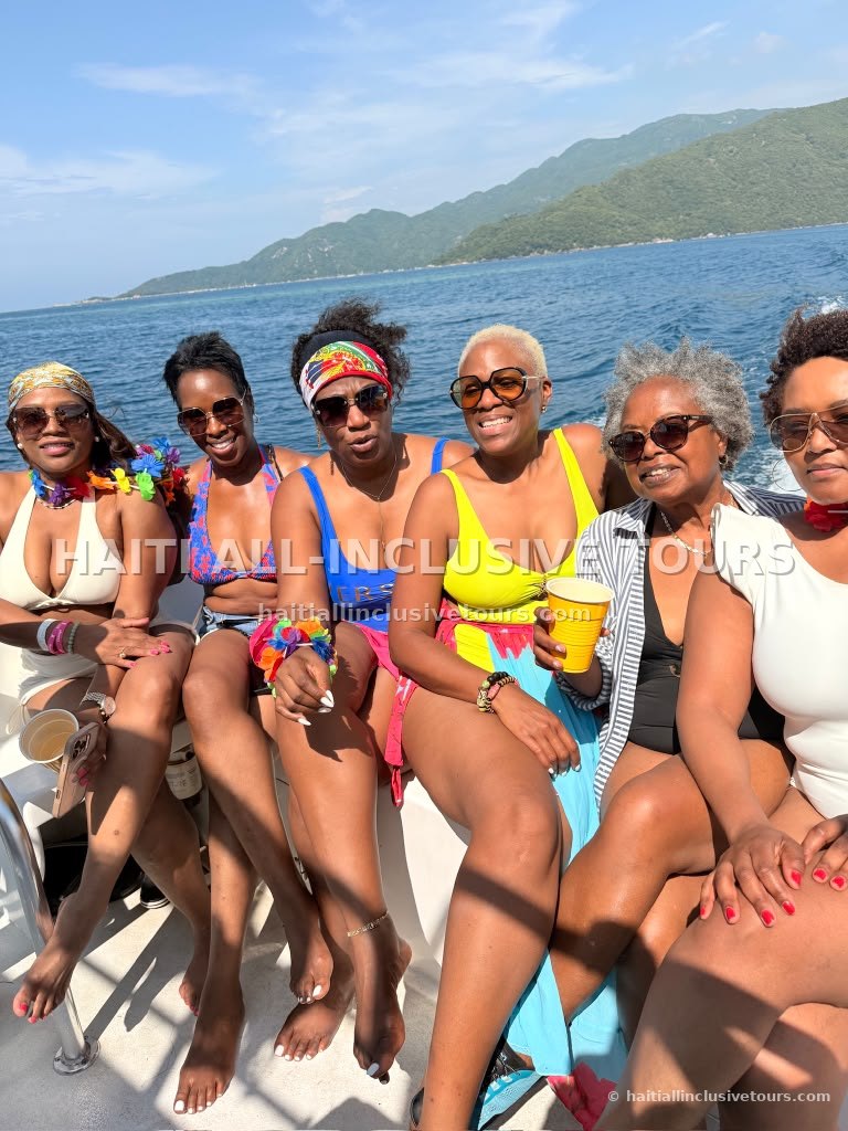 Guests seated along the boat rail with the green Haitian mountains behind
